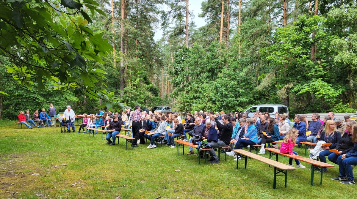 Familien feiern Gottesdienst im Wald bei Mantel