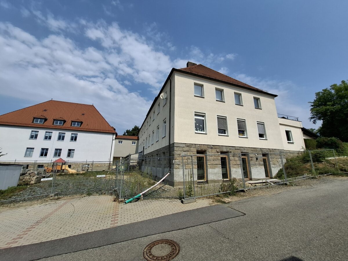 Ziel der Baumaßnahme ist neben der Generalsanierung auch die Erweiterung des Kindergartens einschließlich der Außenanlagen im Krippenbereich. Neben dem KiGa befindet sich die Grundschule (l). Foto: Karl Ziegler